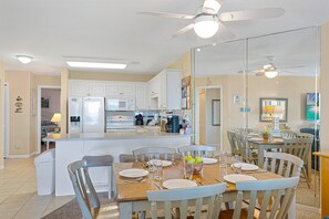 A modern kitchen with white cabinetry, a central island, and a dining area with wooden chairs and a table set for four.
