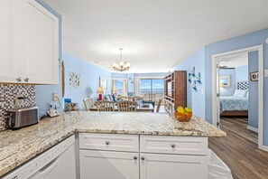 A spacious kitchen with a central island, a dining area with a view, and a bedroom with a bed and a nightstand.