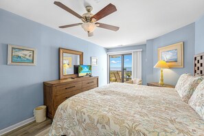 Un dormitorio con cama, cómoda, ventilador de techo y vistas al exterior.
