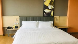 Una habitació d'hotel amb un llit gran, un capçal de llit, taules de nit i un quadre a la paret.