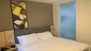 Habitació d'hotel amb llit, tauleta de nit, obra d'art penjada a la paret i una porta.