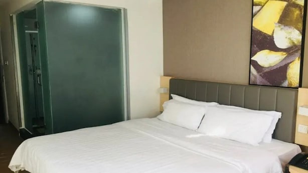 Habitació d'hotel amb un llit, un armari i un quadre a la paret.
