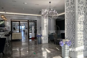 A hotel lobby with a chandelier, a reception desk, and a view into the restaurant area. - Speranta Hotel&villas-all Incl and Private Beach (Balchik)