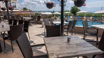 An outdoor patio with wicker furniture, a pool, and umbrellas.