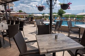 An outdoor patio with wicker furniture, a pool, and umbrellas. - Speranta Hotel&villas-all Incl and Private Beach (Balchik)