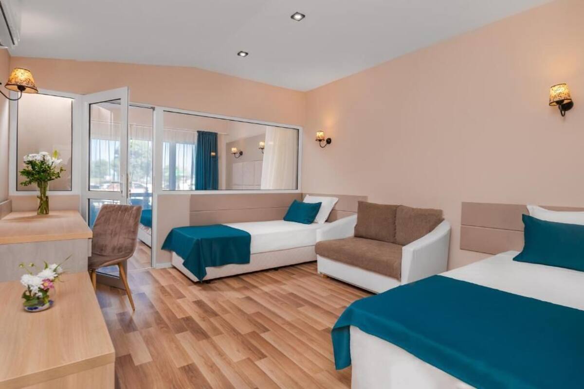 A hotel room with a bed, two sofas, a desk, and a mirror.