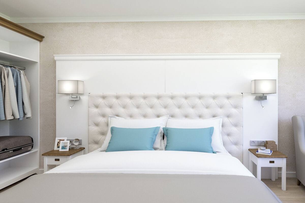 A hotel room with a large bed, two bedside tables, a chair, and a wardrobe.