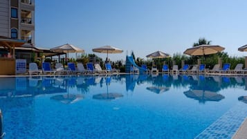 A swimming pool with blue water, surrounded by lounge chairs and umbrellas.