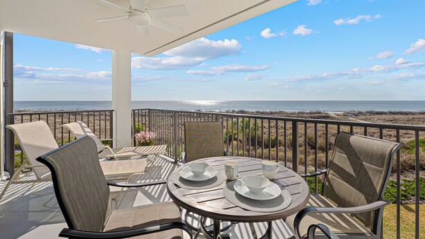 Ein Balkon mit Tisch für zwei Personen, Stühlen und Blick auf den Strand.