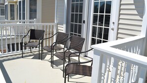 A covered outdoor area with a white railing, featuring a set of four wicker chairs and a table. - Sleeps 10 - 3 bedroom, 2 bath, beach chairs, tags, very close to beach/boardwalk (Ocean City)