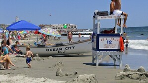 A lifeguard tower with a sign reading "WATCH YOUR CHILDREN" and a boat labeled "OCEAN CITY N.J." in the background. - Sleeps 10 - 3 bedroom, 2 bath, beach chairs, tags, very close to beach/boardwalk (Ocean City)