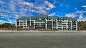 Un hôtel à plusieurs étages doté d’un toit végétalisé, situé près d’une plage et offrant une vue sur l’océan.