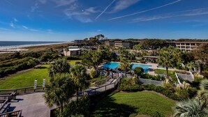 Un complexe hôtelier doté d’une piscine, de palmiers et offrant une vue sur la plage.