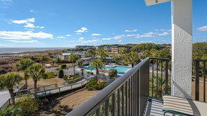 A resort with a pool, palm trees, and a view of the ocean.
