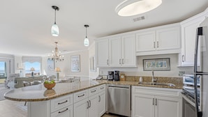 A modern kitchen with white cabinetry, stainless steel appliances, and a granite countertop.