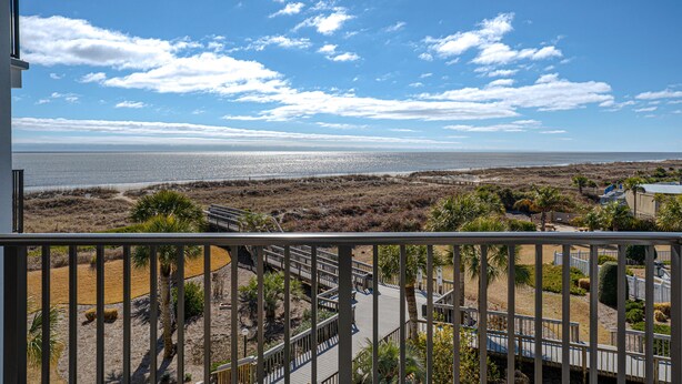 A balcony with a view of the beach and ocean.