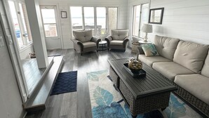 Un salón amplio con un gran ventanal, un sofá, un sillón, una mesa de centro y una lámpara.