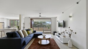 Uma sala de estar moderna com sofá seccional, mesa de centro, televisão e varanda com vista.
