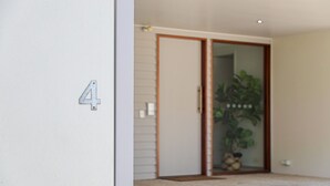 Una stanza con una porta scorrevole in vetro, una pianta in vaso e il numero 4 appeso al muro.