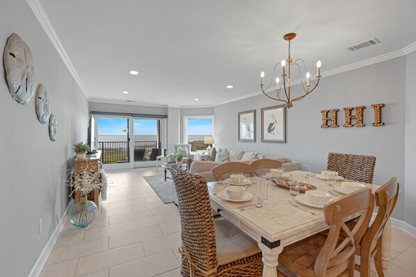 A spacious dining area with a high ceiling, a chandelier, and a view to the outside.