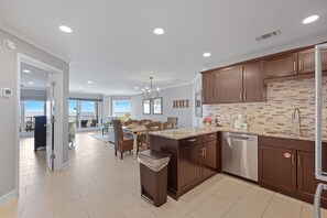 A modern kitchen with dark wood cabinets, a stainless steel dishwasher, and a tiled backsplash.