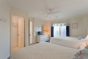 Two-bedroom suite with a classic design, featuring a ceiling fan, dresser, and window with curtains.