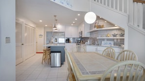 A modern kitchen with a central island, white cabinetry, and a dining area with a table and chairs.