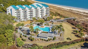 Een meerlaags hotel met een zwembad, toegang tot het strand en uitzicht op de oceaan.