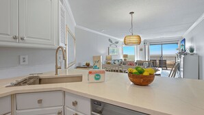 Een keuken met een wit aanrecht, een houten fruitschaal en een hangende lamp.