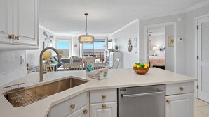 Een moderne keuken met een groot kookeiland, inbouwapparatuur en uitzicht op de eethoek.