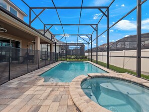 Une piscine dotée d’une zone couverte, entourée d’une clôture, et offrant une vue sur un immeuble d’habitation en arrière-plan.