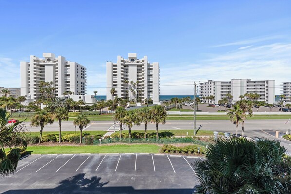 A parking lot with a view of high-rise buildings and palm trees.