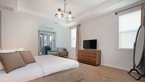 Un dormitorio con cama, cómoda, televisor y espejo.