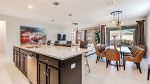 Una cocina moderna con encimeras de granito, electrodomésticos de acero inoxidable y una zona de comedor con sillas de cuero.