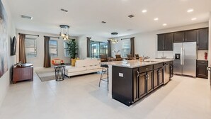 Una cocina moderna con una isla central, muebles oscuros y electrodomésticos de acero inoxidable.