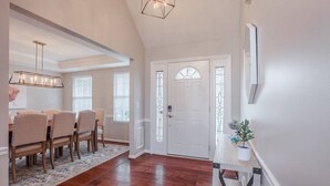 A spacious dining area with a wooden table and chairs, a patterned rug, and a modern pendant light.