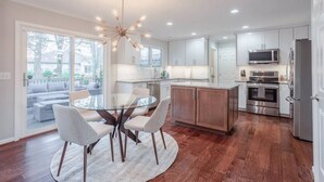 A modern kitchen with a central island, stainless steel appliances, and a dining area with a glass table and chairs.