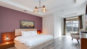 A modern hotel room with a large bed, a desk, and a view of the outside.