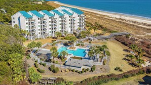 A multi-story hotel with a swimming pool, located near a beach. - Beachfront Hilton Head Villa • Ocean Views & Pool Access (Hilton Head Island)