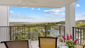 A balcony with a view of a landscaped area, a pool, and a beach. - Beachfront Hilton Head Villa • Ocean Views & Pool Access (Hilton Head Island)