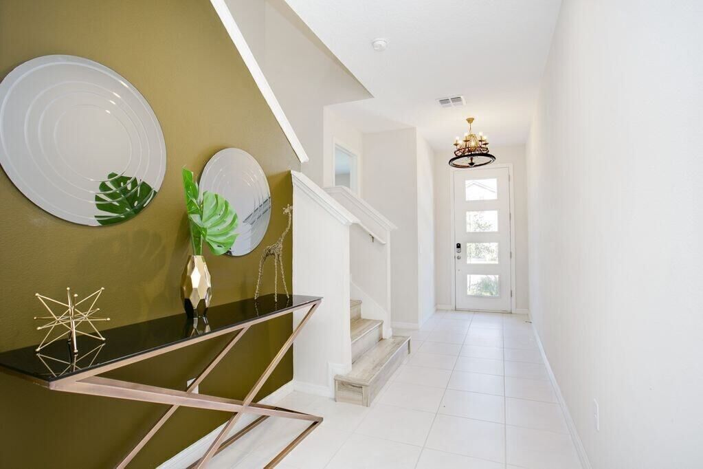 A modern interior with a staircase, a chandelier, and decorative plates on the wall.