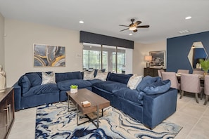 Un salon moderne avec un canapé d’angle, une table basse et un coin repas avec des chaises.