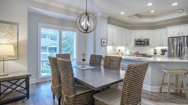A modern kitchen with white cabinets, stainless steel appliances, and a large island.