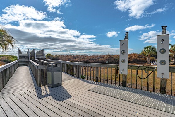 A wooden boardwalk with steps leading to a viewing platform, surrounded by a metal railing and featuring two speaker structures.