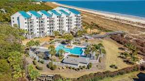 A multi-story hotel with a pool area, surrounded by a beach and palm trees. - Oceanfront Villa | Direct Beach Access, Private Pool, King Suite & Ocean Views (Hilton Head Island)