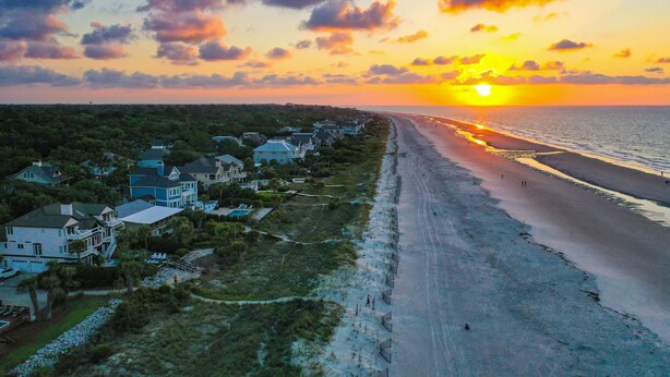 A coastal residential area with houses along the beach, a clear sky, and the sun setting over the horizon. - Forest Beach Villa | Sleeps 6 | Walk to Coligny Plaza, Beach & Dining (Hilton Head Island)