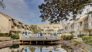 A waterfront apartment complex with balconies, a central pool, and surrounding greenery. - Forest Beach Villa | Sleeps 6 | Walk to Coligny Plaza, Beach & Dining (Hilton Head Island)