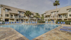 A swimming pool surrounded by lounge chairs and palm trees, with a brick walkway leading to the pool. - Forest Beach Villa | Sleeps 6 | Walk to Coligny Plaza, Beach & Dining (Hilton Head Island)