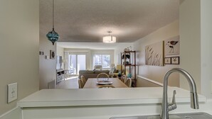 A kitchen with a modern sink, a dining area with a table and chairs, and a view of a balcony. - Forest Beach Villa | Sleeps 6 | Walk to Coligny Plaza, Beach & Dining (Hilton Head Island)