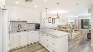 Cocina moderna con armarios blancos, una isla grande y un comedor con mesa y sillas.